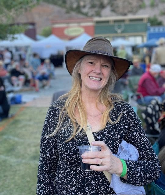 A woman in a hat holding a drink.