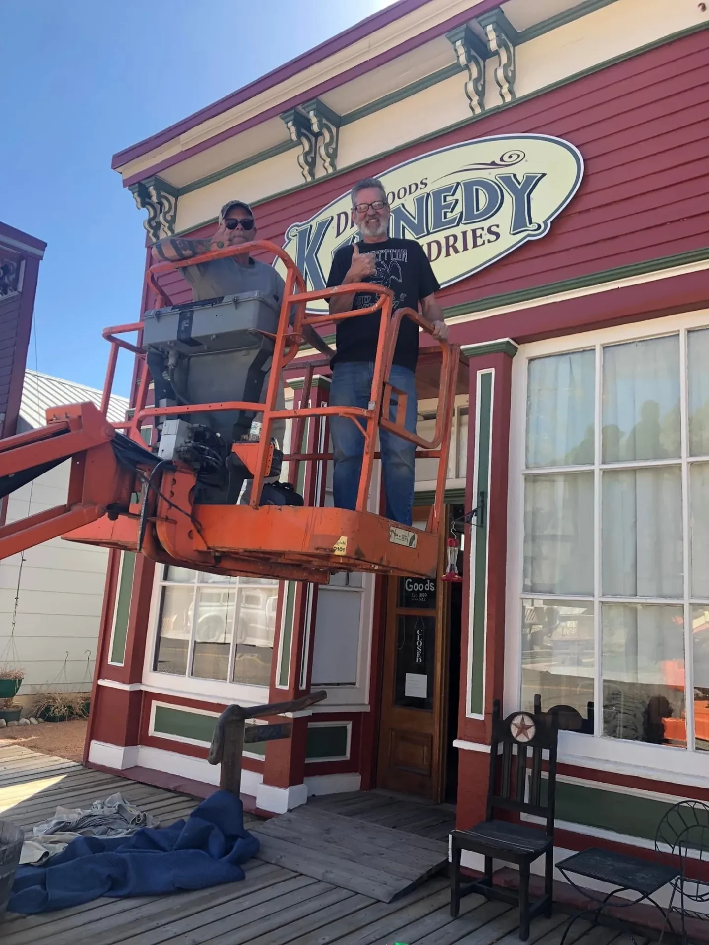 Two men in a cherry picker working on the side of a building.