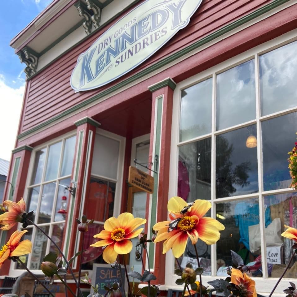 A store front with many flowers in the window.